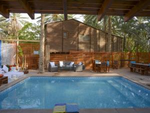 a swimming pool with a house in the background at Diar Abou Habibi in Tozeur