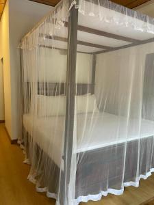 a bedroom with a bed with white curtains at Edward's Bungalow in Tangalle