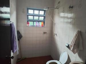 a bathroom with a toilet and a window at Casa de veraneio in Solemar