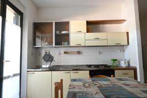 a kitchen with white cabinets and a table at M328 - Marcelli, bilocale con vista mare in Marcelli