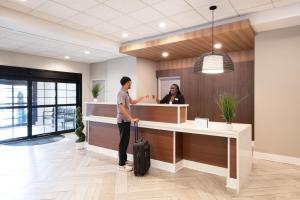 アトランタにあるStaybridge Suites Atlanta Airportの事務所のカウンターに立つスーツケースを持つ男