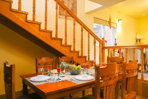 a dining room table with wine glasses on it at Alaya Stays 2 BHK with Garden & Balcony - Villa Harmony in Bhowāli