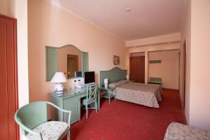 a hotel room with two beds and a desk at Hotel Laurentia in Rome
