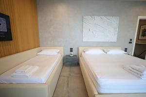 two beds in a room with white sheets and towels at Green Coast Resort V94 in Palasë