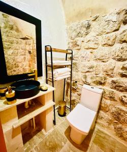 La salle de bains est pourvue de toilettes et d'un mur en pierre. dans l'établissement ŞEHRAZAD OTEL MERDİN masal şehri konağı, à Mardin