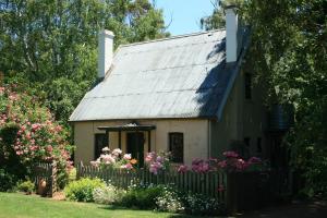 a small house with a fence and flowers at Brickendon in Longford