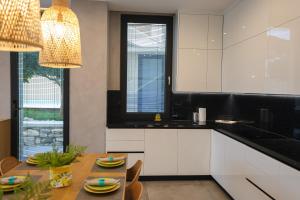 a kitchen with white cabinets and a table with chairs at Green Coast Resort V94 in Palasë