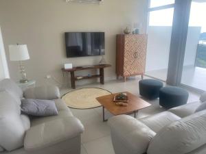 Una sala de estar con un sofá blanco y un televisor. en Pacificdreams, en San Juan del Sur
