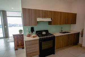Una cocina con gabinetes de madera y un horno de estufa. en Pacificdreams, en San Juan del Sur