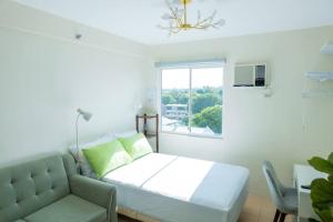 a white bedroom with a couch and a window at Unit 28 Mountain View Studio by Ems in Dumaguete