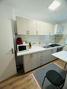 a kitchen with white cabinets and a sink and a microwave at A's apartment in Onești