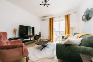 a living room with a couch and a tv at Sunny 2 BR Aptm with Garden Fast WiFi Walk to Seafront in Il-Gżira