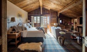 a bedroom with a bed and a couch and a table at Les Chalets du Mont d'Arbois & Spa, Megève in Megève