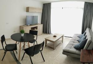 Una sala de estar con un sofá, una mesa y sillas. en Los Juncos 401 Maspalomas, en Playa del Inglés