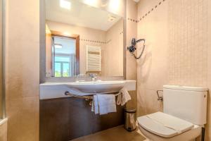 Un baño con inodoro, lavabo y espejo. en ITC Mora by Soho Boutique, en Madrid