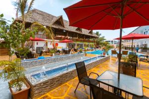 a pool at a resort with a table and an umbrella at Canary Hotel & SPA in Nungwi
