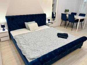 Cama azul en habitación con mesa y sillas en Dave Apartman 3, en Szeged