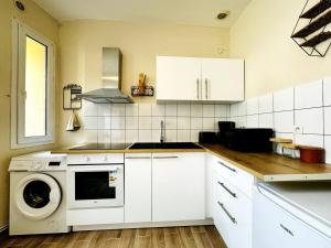 a kitchen with white cabinets and a washing machine at Le Saint Savinien - By 69ALSACELO - Patio Privé - Idéal Couple & Pros - Canapé convertible - Centre Ville - WiFi Fibre - Check-in Autonome - Parking Facile & Gratuit in Sens +14 photos