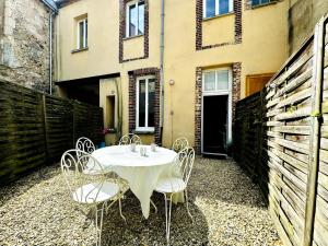 a table and chairs on a patio with a building at Le Saint Savinien - By 69ALSACELO - Patio Privé - Idéal Couple & Pros - Canapé convertible - Centre Ville - WiFi Fibre - Check-in Autonome - Parking Facile & Gratuit in Sens
