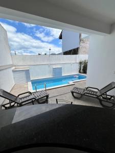 a patio with chairs and a swimming pool at Casa com piscina, 700M da praia in Peruíbe