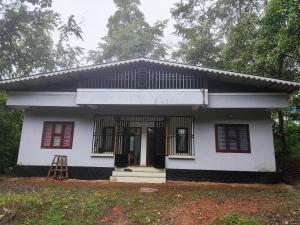 a white house with red windows and a ladder at Brahmagiri Homestay Serviced Villa in Thirunelli