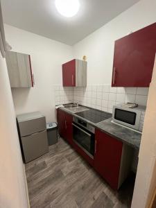 une petite cuisine avec des placards rouges et un four micro-ondes dans l'établissement Schwabacher Goldstück - Wohnung für 2 Personen, à Schwabach