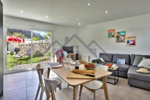 a living room with a table and a couch at LocaLise - M44 - Ty Juzolie -Maison de plain-pied avec jardin clos à deux pas du centre, du port et des plages du Guilvinec - Wifi inclus - Linge de lit inclus - Animaux bienvenus in Le Guilvinec