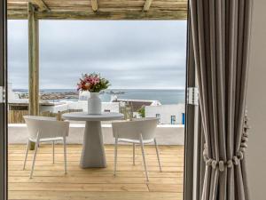 une table et des chaises sur un balcon avec vue sur l'océan dans l'établissement La Baleine, à Paternoster
