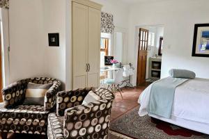 a bedroom with a bed and a couch and a chair at Grey Rabbit Cottage in Montagu