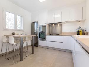 a kitchen with white cabinets and a table with stools at Holiday Home Villa D'Allongue by Interhome in Callian