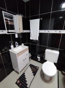 ein schwarz gefliestes Badezimmer mit Toilette und Waschbecken in der Unterkunft Apartamento térreo em palhoça in Palhoça