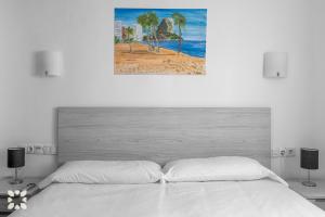 biała sypialnia z łóżkiem i zdjęciem plaży w obiekcie Villa Nani by Abahana Villas w mieście Calpe