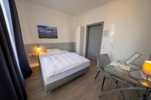 a small bedroom with a bed and a glass table at Mühlenkamp Hotel & Gastronomie in Oelde