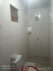 a white bathroom with a toilet and a window at Aluguel por temporada in Mucugê