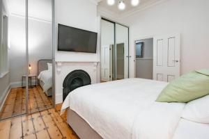 a white bedroom with a large bed and a fireplace at Essex Cottage with garden, 2BR, near Adelaide Showground in Wayville