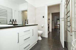 a white bathroom with two sinks and a toilet at Essex Cottage with garden, 2BR, near Adelaide Showground in Wayville +17 photos