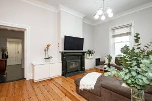 a living room with a couch and a fireplace at Essex Cottage with garden, 2BR, near Adelaide Showground in Wayville
