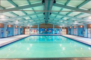 a large swimming pool with blue walls at Tucker’s Retreat in Dymchurch