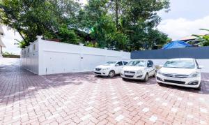 three cars parked in a parking lot next to a fence at Treebo Premium Cochin Airport, 5 min From Cochin Airport in Cochin +41 photos