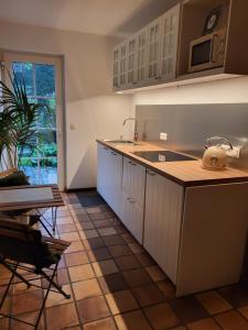a kitchen with white cabinets and a sink and a table at B&B Le Bois de Champia in Huy