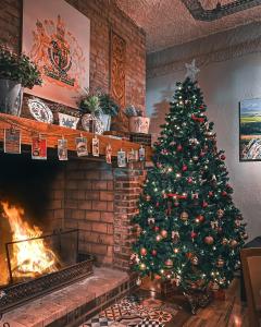 einen Weihnachtsbaum im Wohnzimmer mit Kamin in der Unterkunft Hotel Britanico Express in Gramado