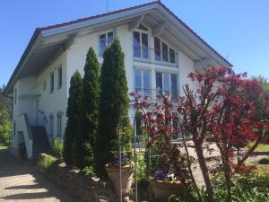 a white house with trees and flowers in front of it at Chiemgau-ROOM, helles Souterrain, eigene Terrasse in Riedering