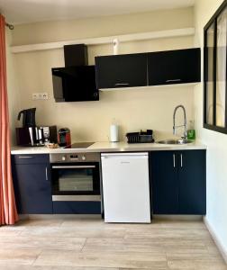 a kitchen with blue cabinets and a white refrigerator at Le Jardin Privé, appartement standing, piscine, terrasse, jardin, parking privé in Cayenne +5 photos