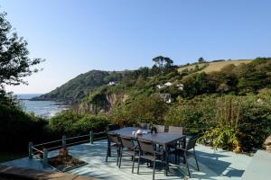 a table and chairs sitting on a patio overlooking the ocean at Beach Front House with Stunning Sea Views and Free Use of a Local Indoor Pool in Talland