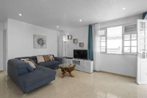 Una sala de estar con un sofá azul y un televisor. en Villa Nayah, en Sainte-Luce
