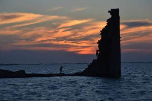 een persoon op een pier in het water bij zonsondergang bij Casa De Grande in Cambados