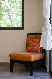 a brown leather chair with a red pillow on it at Lovely Villa 1-BR Villa Miguel in Chemuyil
