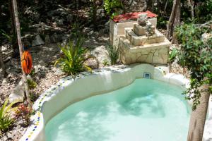a small swimming pool in a garden with a statue at Lovely Villa 1-BR Villa Miguel in Chemuyil