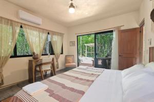 a bedroom with a bed and a desk and windows at 1-BR Gem Apartment Villa Sofia in Chemuyil