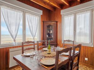 QuinévilleにあるHoliday Home Les pieds dans l'eau by Interhomeのテーブルと椅子と窓のあるダイニングルーム